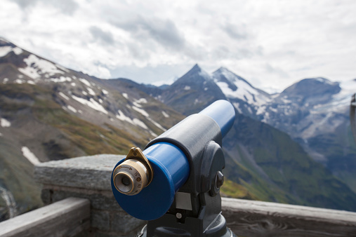 Looking at a high mountain peaks by telescope.
