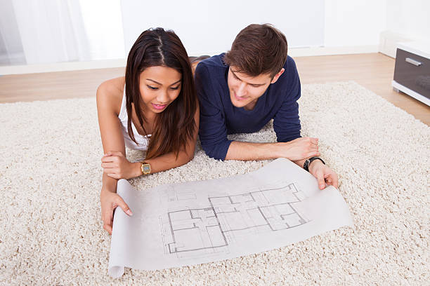 istock Couple Looking At Blueprint While Sitting On Rug 516354851