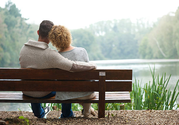 Rear view couple sitting on bench outdoors Rear view of a happy couple sitting together on bench outdoors vista posterior stock pictures, royalty-free photos & images