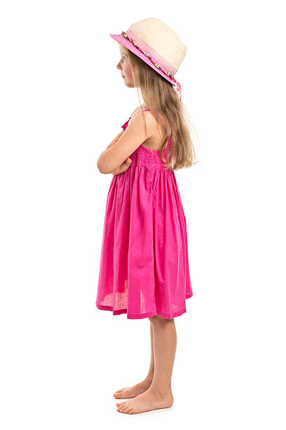 Young girl in blue shirt and headband with cancer in front of a pink background.