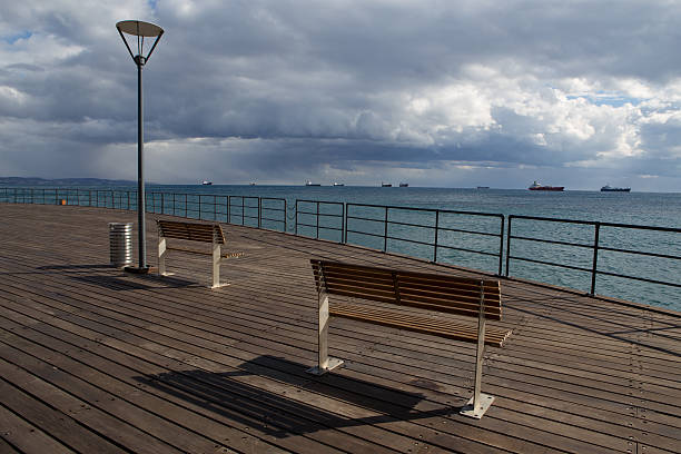 Wooden pier on the beach. Ships at sea. Limassol's seafront promenade. Cyprus.