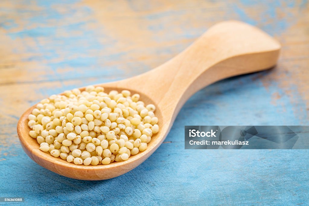 millet grain on wooden spoon millet grain on a wooden spoon against blue painted grunge wood Blue Stock Photo