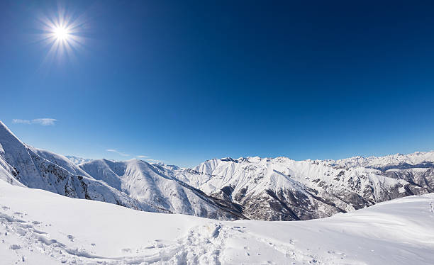 Sun star glowing over snowcapped mountain range, italian Alps
