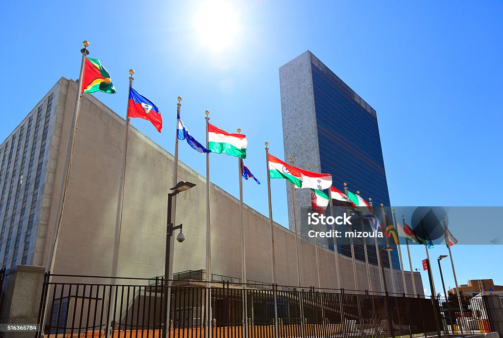 United Nations Headquarters with waving flags in New York, USA New York, USA: United State Headquarters with the members flags erected on the poles. United Nations Building Stock Photo