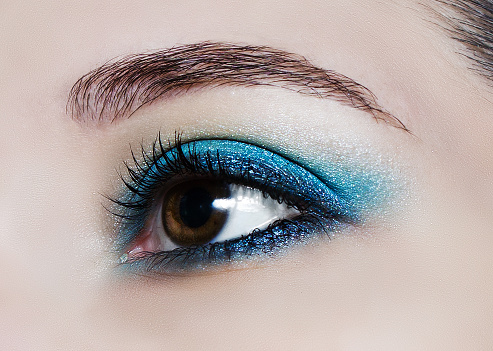 Brown eye makeup in close up. Make up trend: blue shiny eyeshadows.