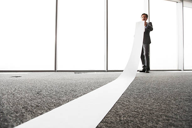 Office worker unrolling long sheet stock photo