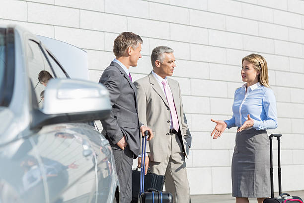 istock Businesspeople with luggage discussing outside car 516372497