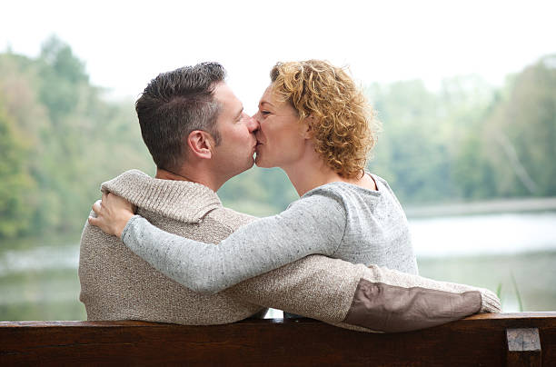 istock Happy couple kissing on park bench 516372761