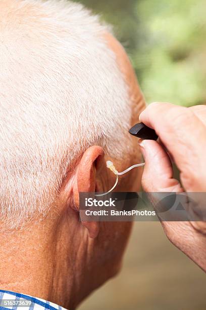 Senior Man Installing Hearing Aid In Ear Stock Photo - Download Image Now - Hearing Aid, Senior Adult, 70-79 Years