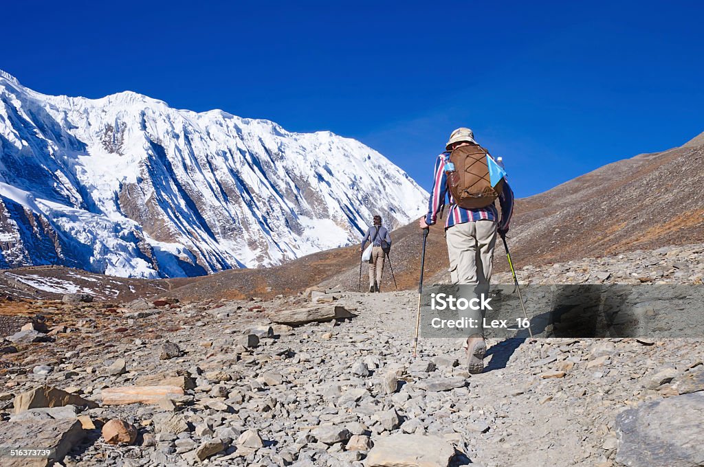 Two trekkers running on the road against Tilicho Two trekkers running on the road against Tilicho Lake Annapurna Conservation Area Stock Photo