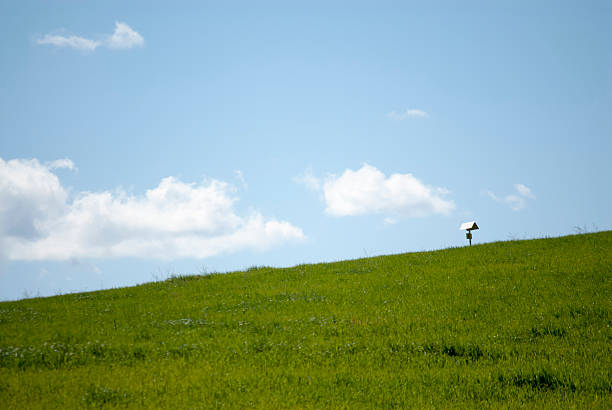 Green grass field with background mailbox cropped with white clouds on blue sky