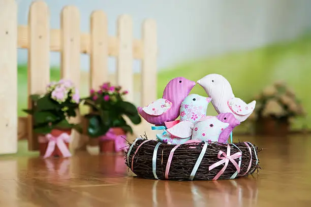 Spring decorative birds in a nest on a wooden floor. Easter decorations. Textile tilde toys of handwork