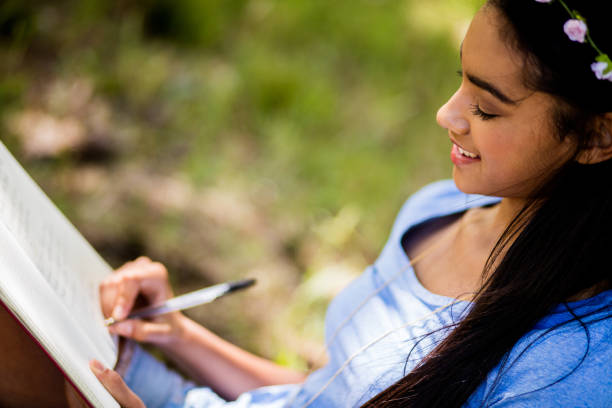 istock Mixed Race Person sitting outside writing in journal 516394900