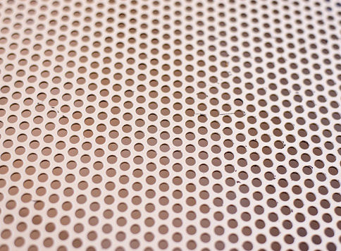 Background texture of a mesh grid with holes in a repeat uniform pattern viewed at an oblique receding angle, full frame