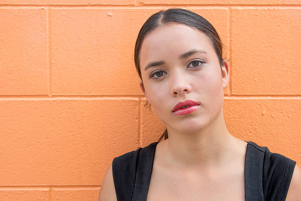 istock Young woman standing in front of orange brick wall 516397818