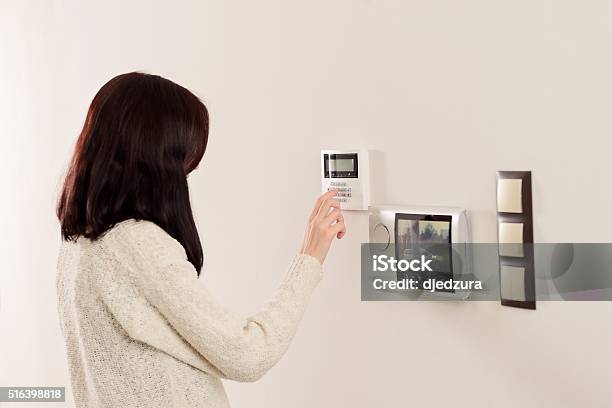 Woman Entering Code On Keypad Of Home Security Alarm Stock Photo - Download Image Now