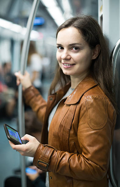 istock brunette girl using cell phone and smiling at subway 516402280