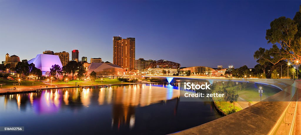ADE river Rise 2 panorama brightly lit Adelaide city CBD with foot bridge across Torrens river. Illumination reflecting in calm waters at sunrise. Adelaide Stock Photo