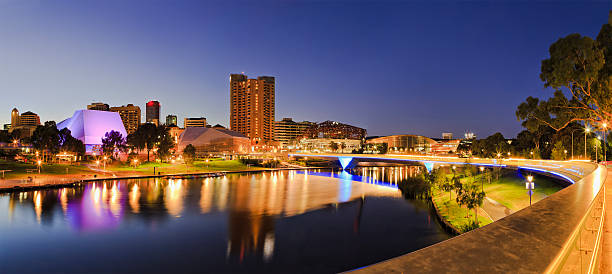 ADE river Rise 2 panorama brightly lit Adelaide city CBD with foot bridge across Torrens river. Illumination reflecting in calm waters at sunrise. adelaide stock pictures, royalty-free photos & images