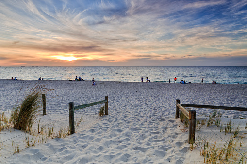 access and entrance to Cottesloe beach of Perth city in Western Australia on Indian coast. Relaxing people in a distance enjoying beautiful susnet over horizon and water.