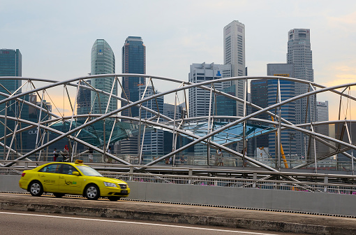 Singapore - August 23, 2014: Taxi passes along pedestrian The Helix Bridge. Bridge won the 'World's Best Transport Building' award at the World Architecture Festival in the 2011.