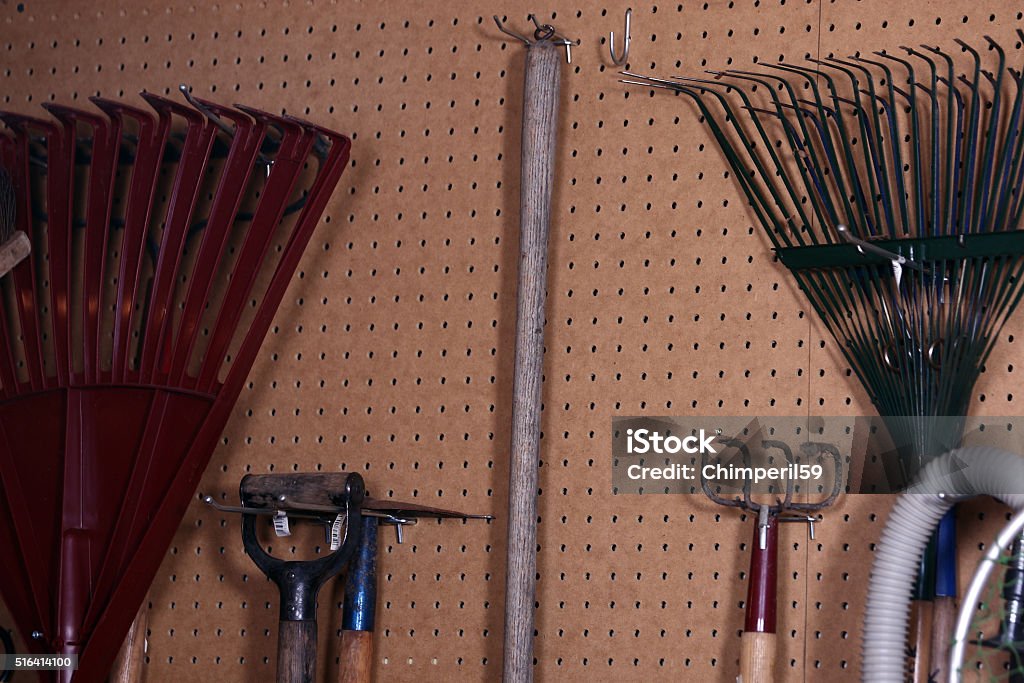 household tools tools hang indiscriminately on pegboard on the wall of the shop. Gardening Equipment Stock Photo