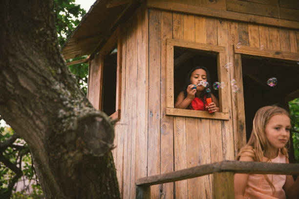 istock Little girls playing in a treehouse and blowing bubbles 516414566