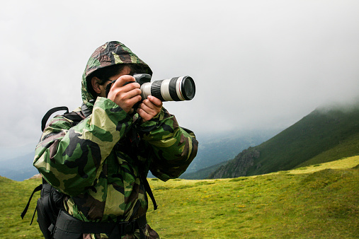 Nature photographer in camouflage clothing using a telephoto lens