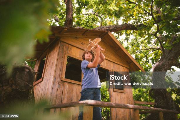 Boy In A Treehouse Daydreaming With His Toy Wooden Plane Stock Photo - Download Image Now