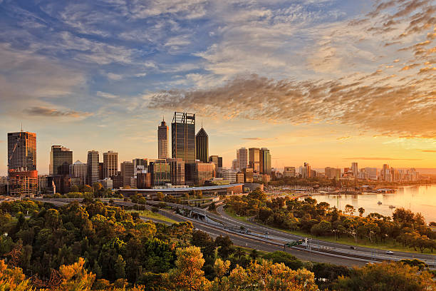 PERTH city gold light park Gold warm sun light litting CBD of Perth city as seen from Kings park with green trees and highway entering the city. western australia stock pictures, royalty-free photos & images