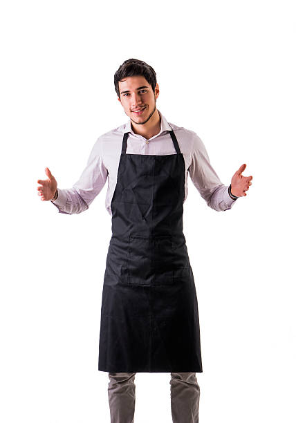 Young chef or waiter posing, wearing black apron and shirt isolated on white background, holding empty space between hands