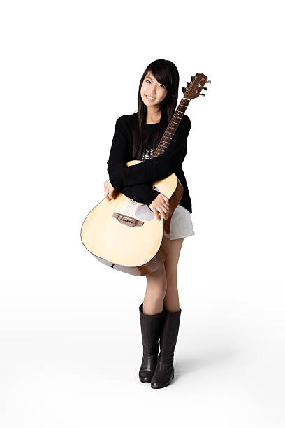 Portrait of young beautiful Asian woman with guitar against arched gray doorway horizontal shot