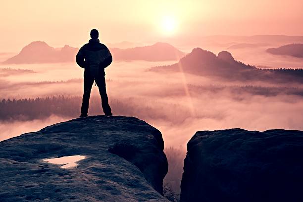 istock Man onf sandstone rock  watching to Sun. Beautiful moment 516423318
