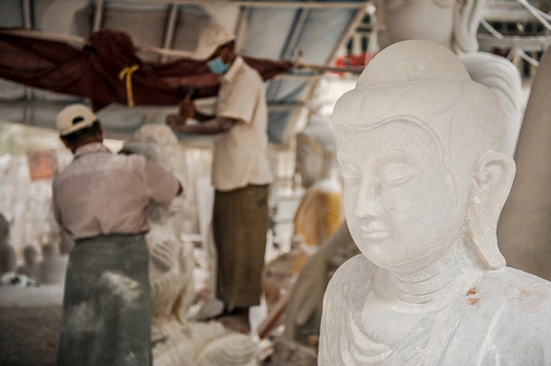 Mandalay, Myanmar - March 15,2011:A Myanmar carver using a tool on a marble to carving a statue Buddha in Mandalay of Myanmar.