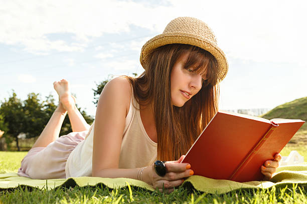 istock Atractive young female reading book in the park 516441821