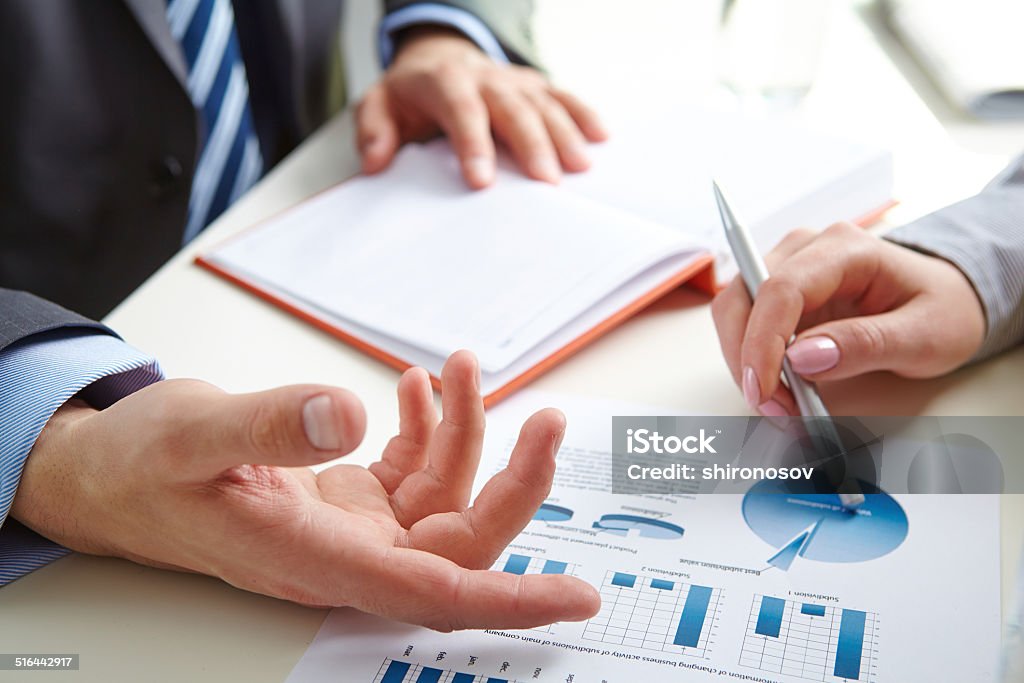 Paper discussion Male hand pointing at paper containing data about economic situation Business Stock Photo