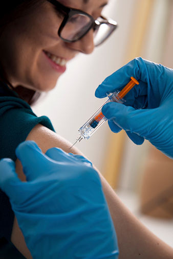 Nurse at pharmacy clinic or doctor's office giving flu shot to a female patient.  Syringe, needle.