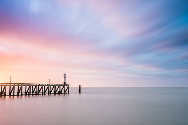 Lighthouse at the end of a pier. stock photo