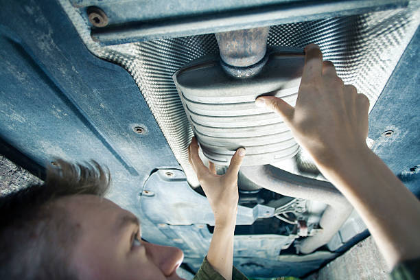 Mechanic checking exhaust pipe Male mechanic replacing exhaust pipe under car exhaust pipe photos stock pictures, royalty-free photos & images