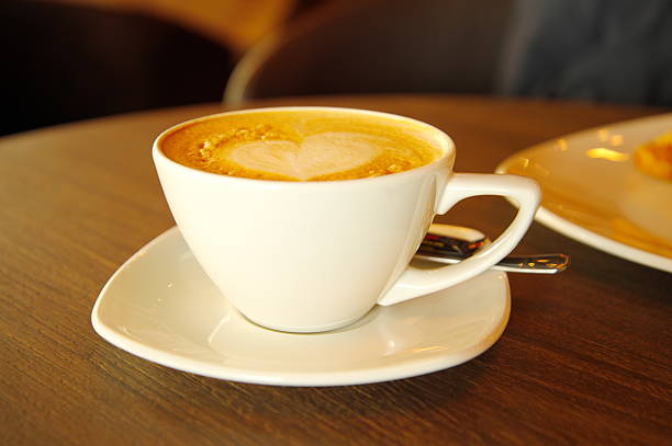 istock cappuccino hot coffee in white cup on wood table 516449752