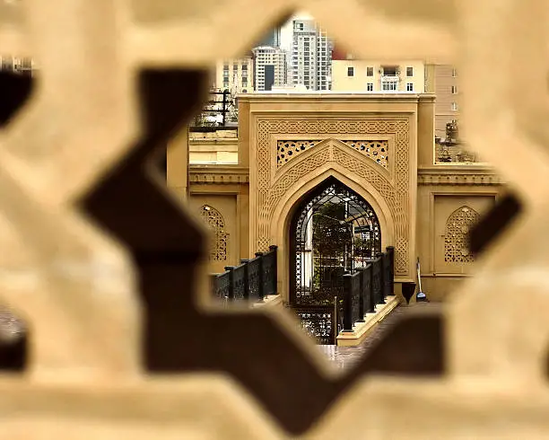 A view into the courtyard of a modern mosque in the centre of Baku, Azerbaijan, seen through a gap in a decorative wall.