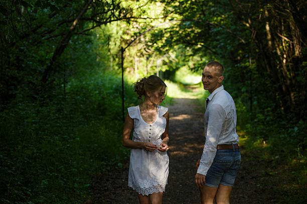 Happy mid 20's couple having fun in local park. Both smiling and looking at camera. It's summer sunsetHappy young couple in summer parkHappy mid 20's couple having fun in local park. Both smiling and looking at camera. It's summer sunset