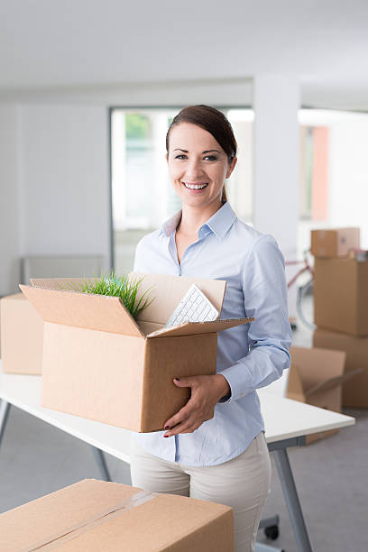 istock Happy woman carrying boxes into her new office 516455966