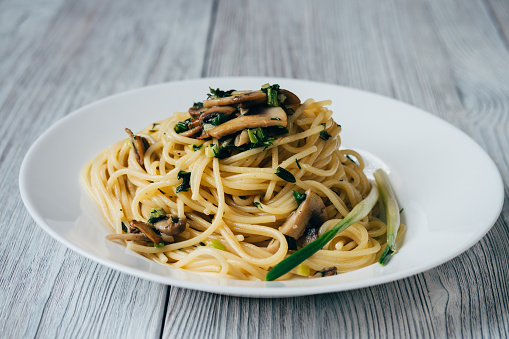 Spaghetti with mushrooms and onions on a white plate