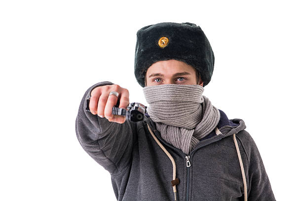 istock Man in winter hat and scarf threatening with gun 516457544