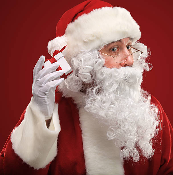 istock Santa Claus holding red giftbox by his ear 516461443