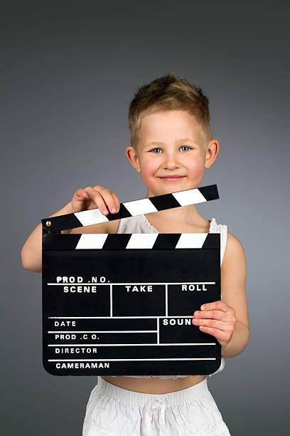 istock Smiling kid holding movie clapper board. 516461835