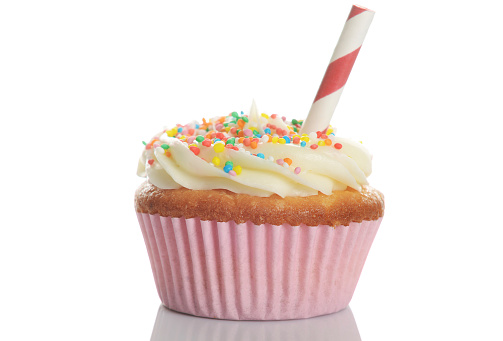 Cupcake, with buttercream flavor and sprinkles on top of sugar cream in a pink paper patty pan isolated on a white background