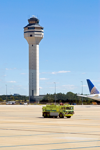 Fairfax County, Virginia - September 14, 2013: A Metropolitan Washington Airports Authority fire engine crosses the tarmac near the airport control tower and a United Airlines passenger airplane.