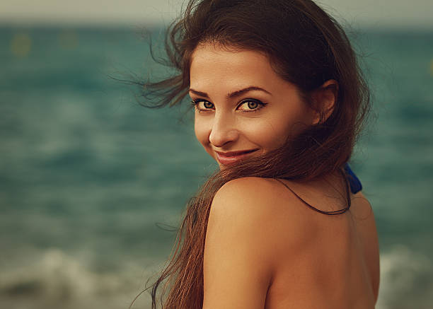 sorridente jovem mulher olhar feliz no fundo do mar.  plano aproximado - human hair retro revival old fashioned beauty imagens e fotografias de stock